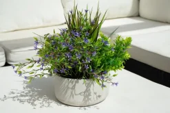 Outdoor centerpiece of small purple flowers and mixed foliage, 14 x 16"